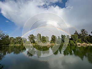 double rainbow over a lake with trees in the background