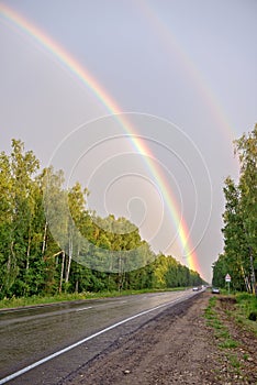 Double rainbow over road and forest