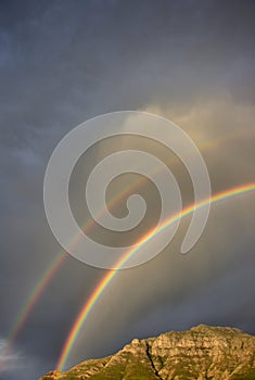 A double rainbow over Stellenbosch Mountain against a cloudscape