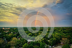 Double rainbow in the sky at sunset over a town all covered with greenery