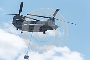 Double rotor, heavy airlift, military helicopter, in flight, carrying cargo.