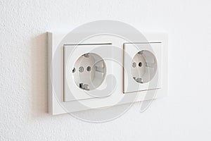 Double socket, new electric plug on white wall