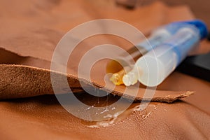 Double syringe with epoxy gel gluing and spilling on genuine brown leather texture, soft focus