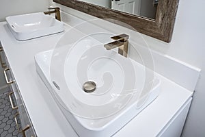 Double two white sinks with modern and elegant gold fixtures with a mirror in a newly renovated master bathroom