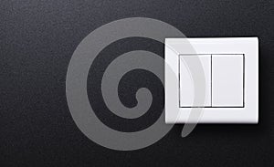 The double wall switch of white color on a black background.