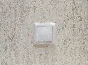 Double white electric switch on a light wall