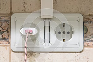 Double white outlet on the tile kitchen with a charge from the mobile phone