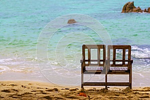 Double wooden chairs to sit at the sea on the beach