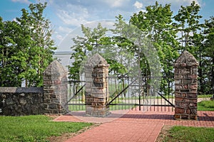 Double wrought-iron gate and stone pillars entrance gates to rural property with no people around only greenery like