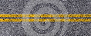 Double yellow lines on asphalt street roadway surface texture background.