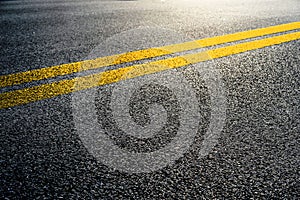 Double yellow lines on asphalt street roadway surface texture background.