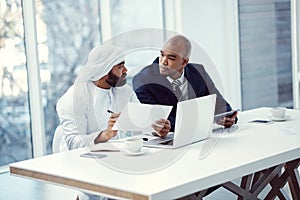 Doubled up on business skills to make success happen. two businessmen using a digital tablet and laptop while having a