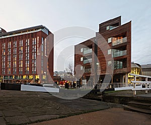 the doubletree hilton hotel in leeds next to the dock and canal lock gates with apartment developments illuminated at twilight