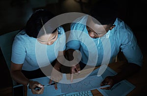 Doubling down gets the books balanced. a young businesswoman and businessman analysing financial reports during a late