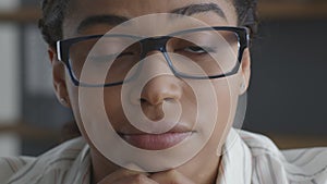 Doubt concept. Close up of young sceptical african american woman wearing eyeglasses looking seriously at camera