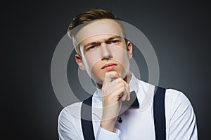 Doubt, expression and people concept - boy thinking over gray background