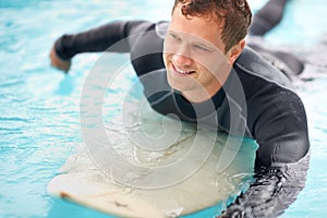 When in doubt, paddle out. Shot of a handsome young man enjoying a surf in clear blue water.