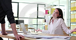 Doubtful business woman shrugging her shoulders in conversation with boss