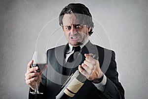 Doubtful businessman with a glass and a bottle of wine