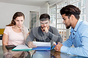 Doubtful couple reading contract with agent