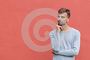 Doubtful man in thinker pose on isolated red wall background