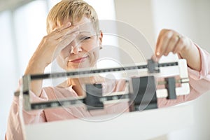 Doubtful Woman Adjusting Weight Scale