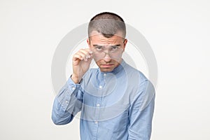 Doubtful young hispanic man looking with disbelief expression through glasses.