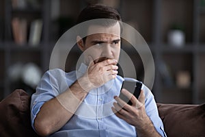 Doubtful young man hold phone hesitate before make call photo