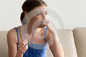 Doubtful young woman holding wedding ring, hesitating about marr