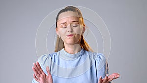 Doubtful young woman refusing gesture hesitating on gray background in studio