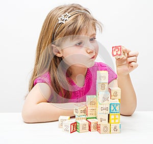 A doubting girl playing with wooden cubes