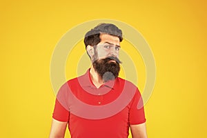 doubting hipster male with beard on yellow background, portrait