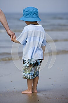 Doubting little boy standing with his feet in the sea