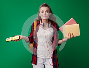 Doubting student woman choosing between books and video game