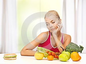 Doubting woman with fruits and hamburger