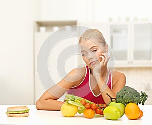 Doubting woman with fruits and hamburger