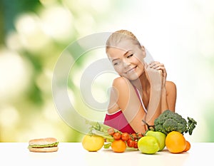 Doubting woman with fruits and hamburger