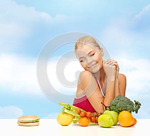 Doubting woman with fruits and hamburger