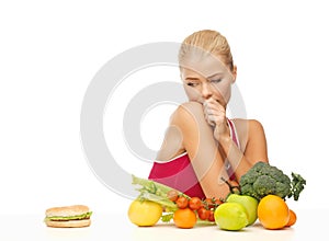 Doubting woman with fruits and hamburger photo