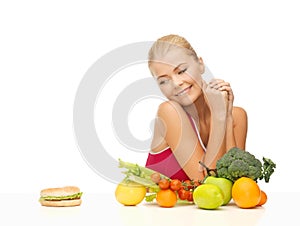 Doubting woman with fruits and hamburger photo