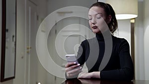 doubting woman is sitting at home with mobile phone, deciding calling or not, waiting call