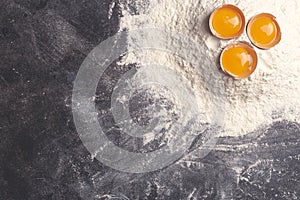 Dough, baking and cooking background. Flour and eggs on a dark wooden kitchen background as ingredients for a recipe and