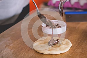 Dough with the chocolate in the middle being put by spoons