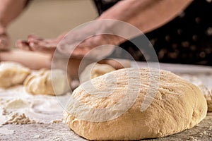 Dough close-up. Hands baking dough with rolling pin on wooden table. Old woman hands hands keep rolling pin with flour