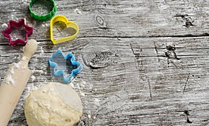 Dough, cookie cutters, rolling pin on a light wooden background