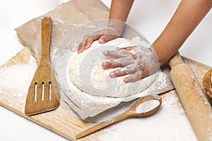 dough in flour kneading childrens hands, one kid, child helps parents in kitchen, concept of a happy childhood,