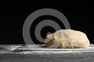 The dough lies on a board with flour. On a black background. cooking bread, focoque, pizza, pasta. Baking and cooking. bakery
