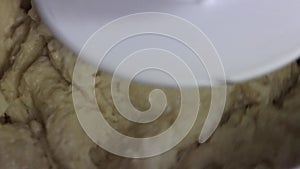 Dough mixture kneading in automatic kitchen appliance as chef mixes ingredients. Slow panning left.