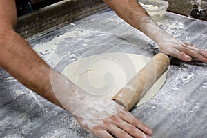 Dough with motion hands with rolling pin on wooden table