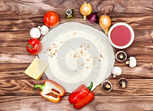 Dough for pizza with raw pizzas ingredients on the wooden background. Top view